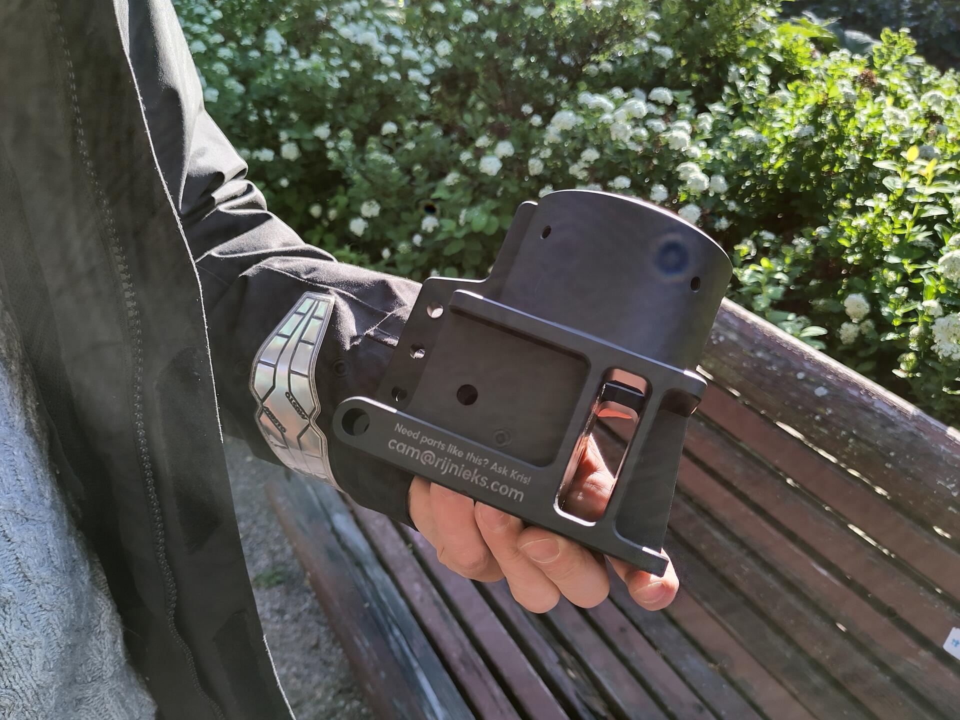 A photo of an Elliot mast base in a hand of a human, with park in the background