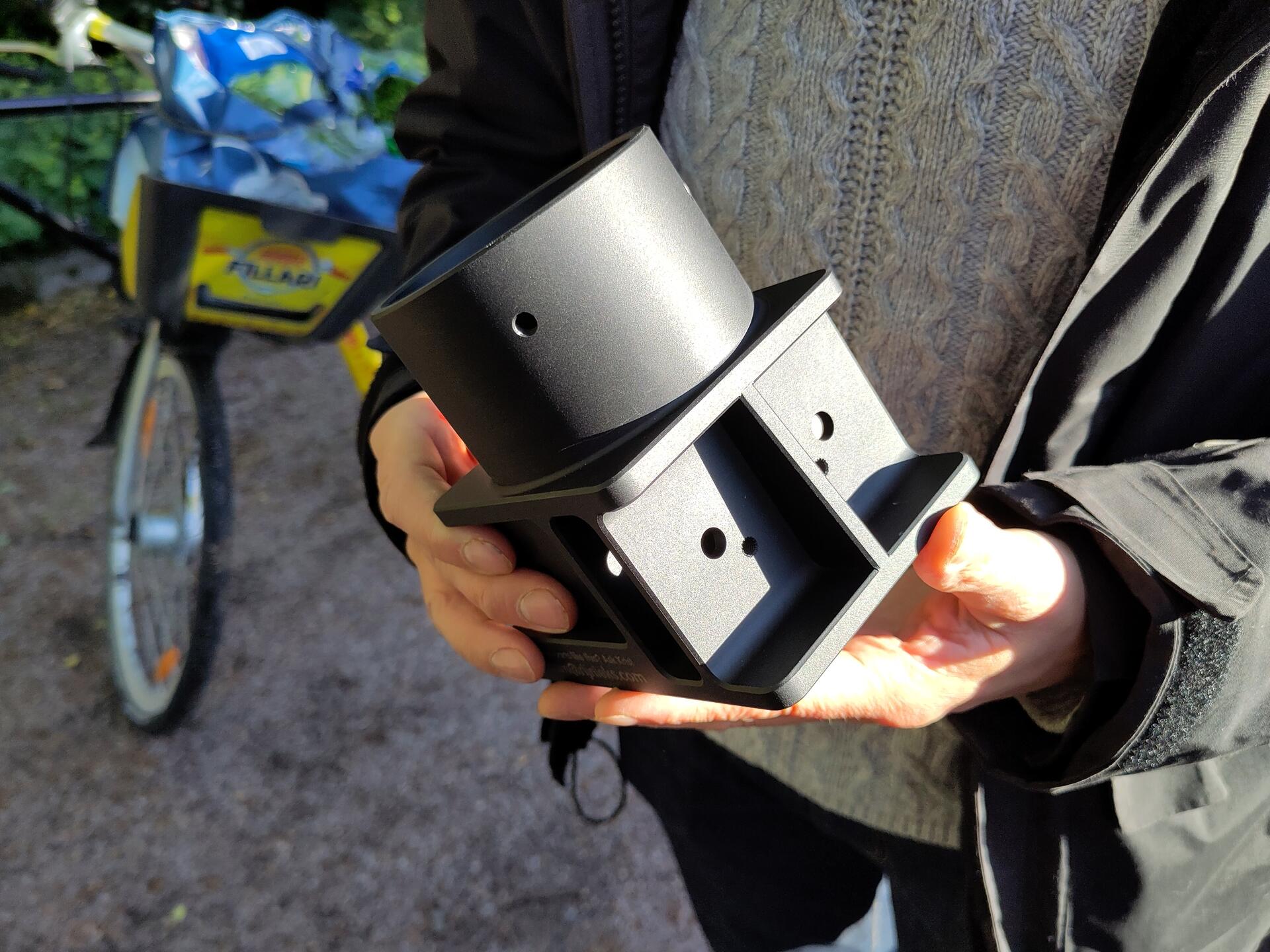 A photo of an Elliot mast base in a hand of a human, with an Alepa bike in the background